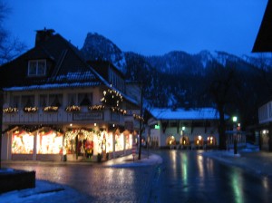 Shop windows sparkle and glow against the evening sky in the Alps